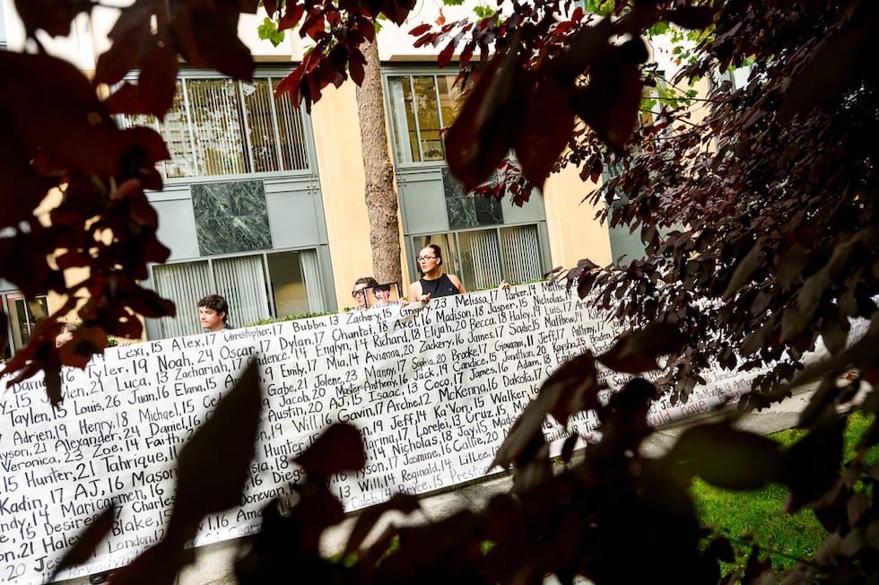 Lennon Torres de Heat Initiative sostiene un cartel con los nombres de jóvenes que, según...