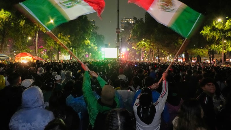 Mexican fans wave flags as they watch the World Cup round of 32 soccer match between Mexico...