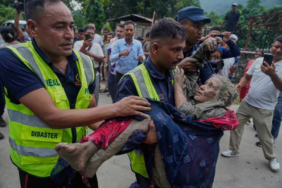 Rescatistas trasladan a una víctima de las inundaciones repentinas a un lugar seguro a orillas...