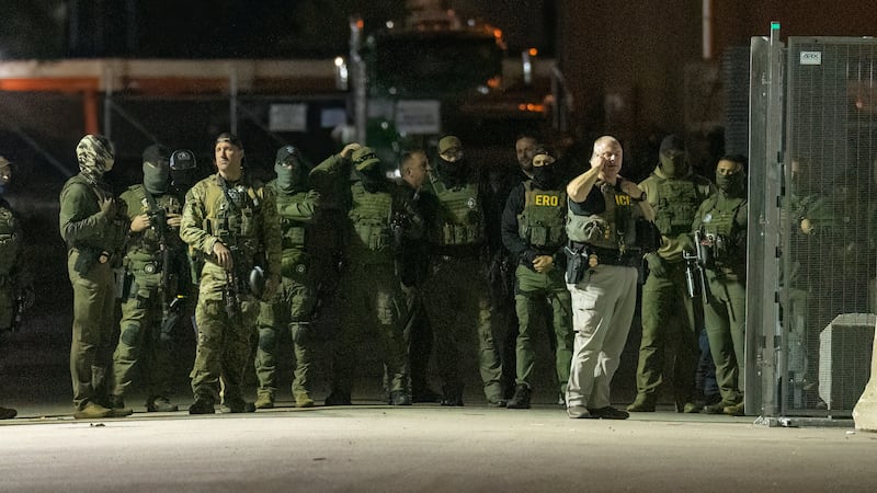 Federal law enforcement officers stand guard in the open gate of the fence built on Beach...
