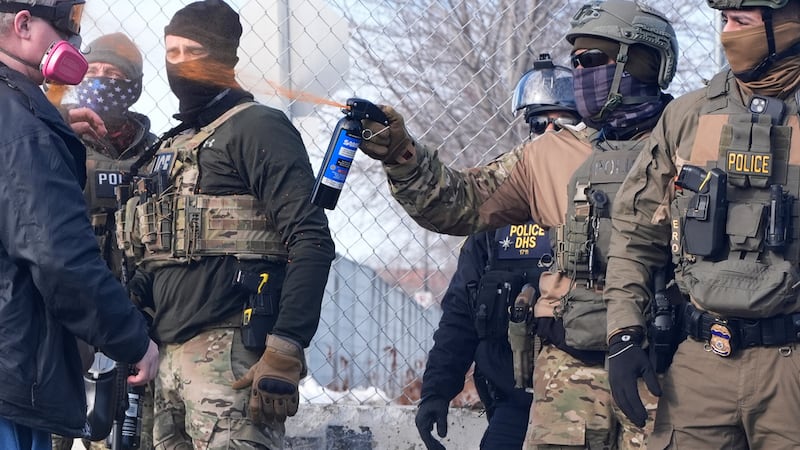 Un agente del Servicio de Inmigración y Control de Aduanas (ICE) rocía con gas pimienta a un...