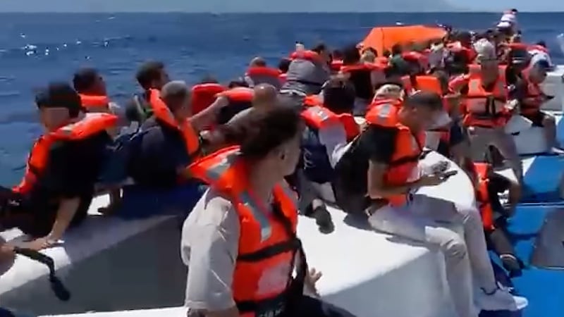 En esta imagen capturada de un video, pasajeros con chalecos salvavidas esperan sobre una...