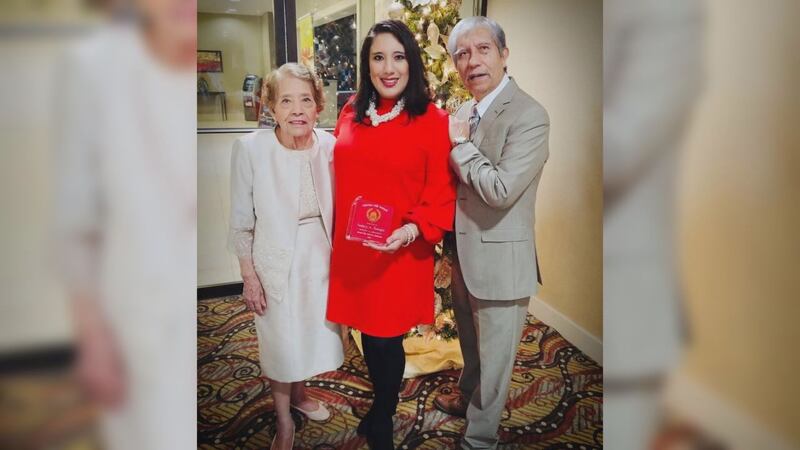 Nancy Rangel sostiene un premio junto a sus padres.