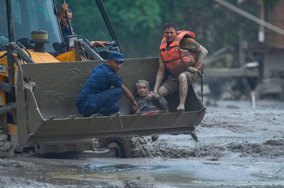 Rescatistas usan una excavadora para poner a salvo a las víctimas de una inundación a lo largo...