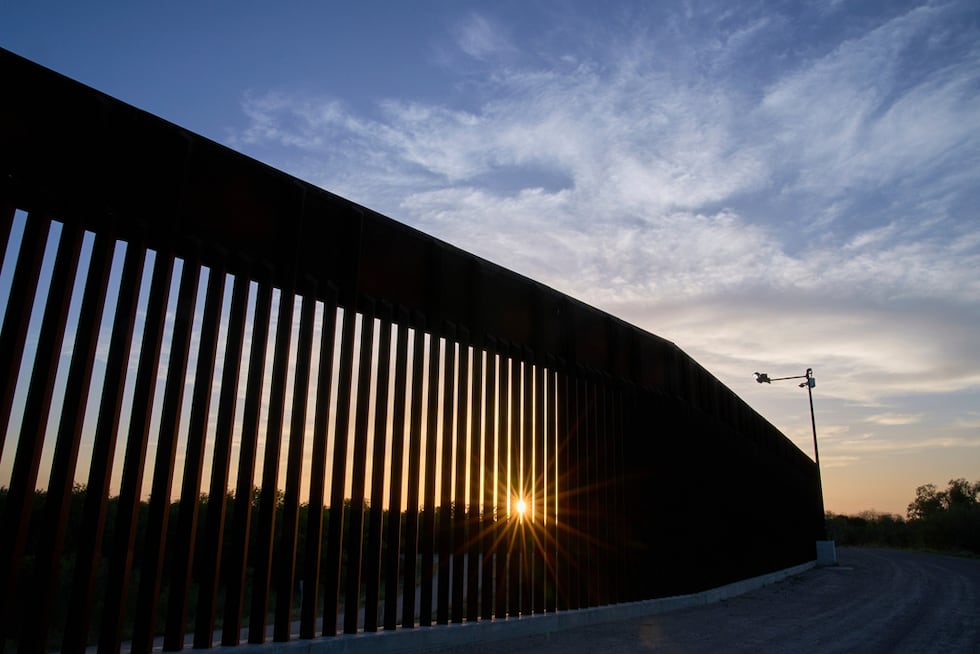 El sol se oculta detrás de un tramo del muro fronterizo, el 18 de junio de 2025, en Mission,...